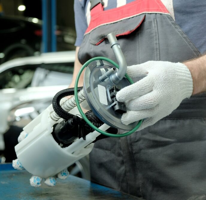 A mechanic wearing white gloves installs and electric fuel pump after learning the differences between mechanical vs electric fuel pumps