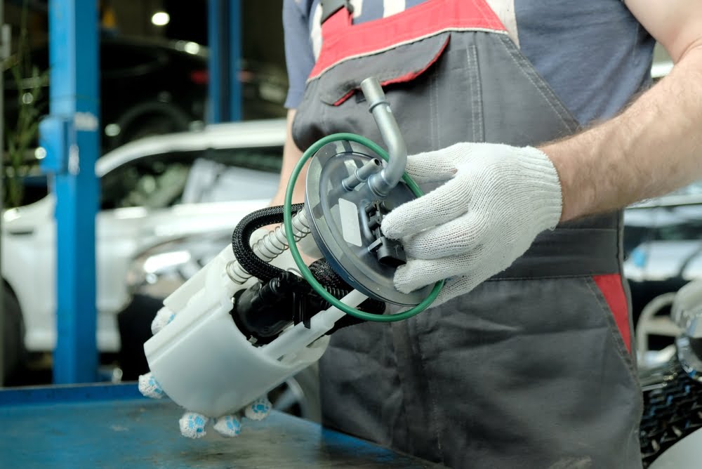 A mechanic wearing white gloves installs and electric fuel pump after learning the differences between mechanical vs electric fuel pumps