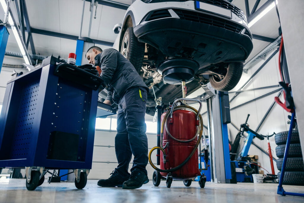 A mechanic is using a car lift to work on a vehicle he knows the benefits and differences between used vs new car lift