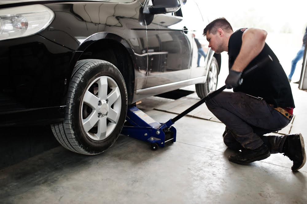A mechanic utilizing a used car jack - buying used equipment | purchase used equipment