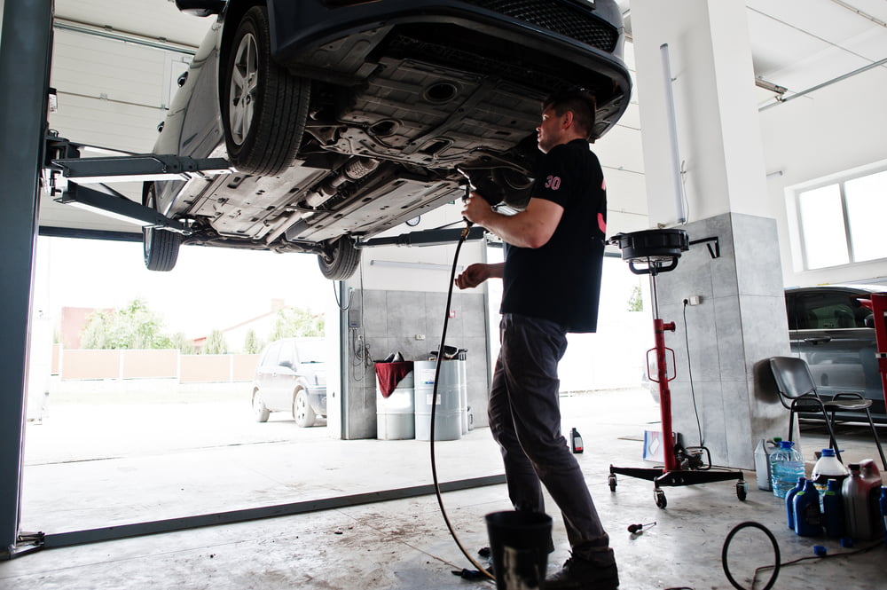 Mechanic utilizing a used car lift - buying used equipment | purchase used equipment
