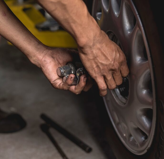 mechanic screws on lug nuts onto the tire of a serviced car