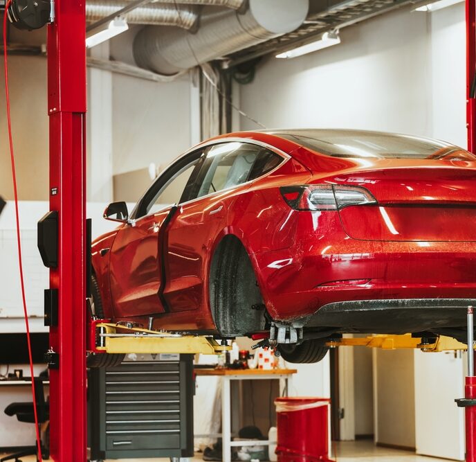 The rear hub of a car without a wheel. Removed wheel in the foreground. Electric vehicle maintenance at a Professional Workshop. Repairing the EV transport. Car lifted in auto service shop.