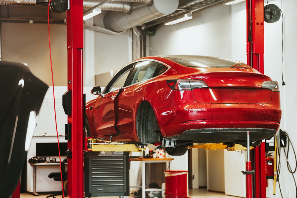 The rear hub of a car without a wheel. Removed wheel in the foreground. Electric vehicle maintenance at a Professional Workshop. Repairing the EV transport. Car lifted in auto service shop.